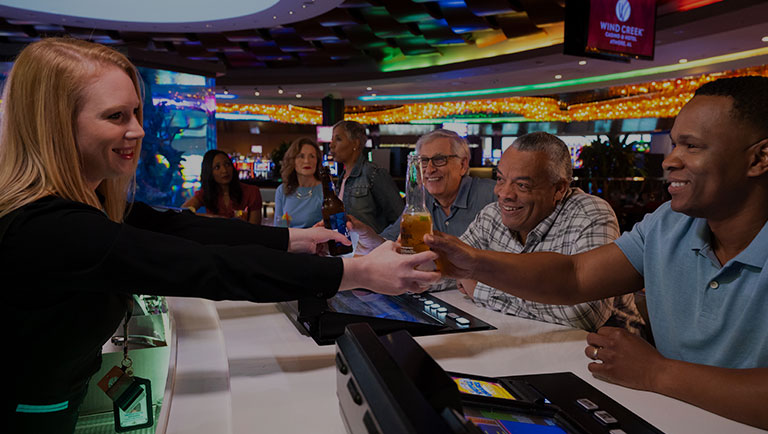 A bartender handing a bottle of beer to a smiling customer at the Center Bar.