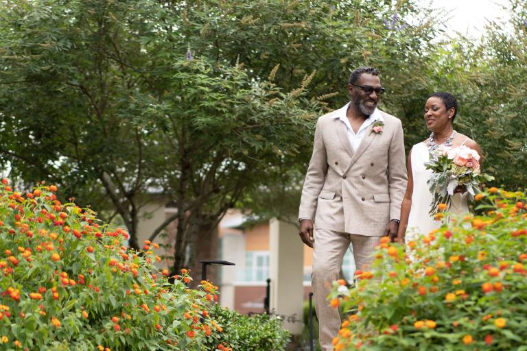 Bride and groom stroll through lush landscaping at Wind Creek Atmore