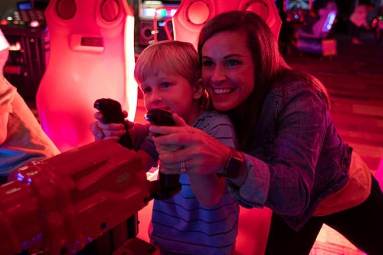 A woman helps her child play a game at the Wind Creek Atmore arcade