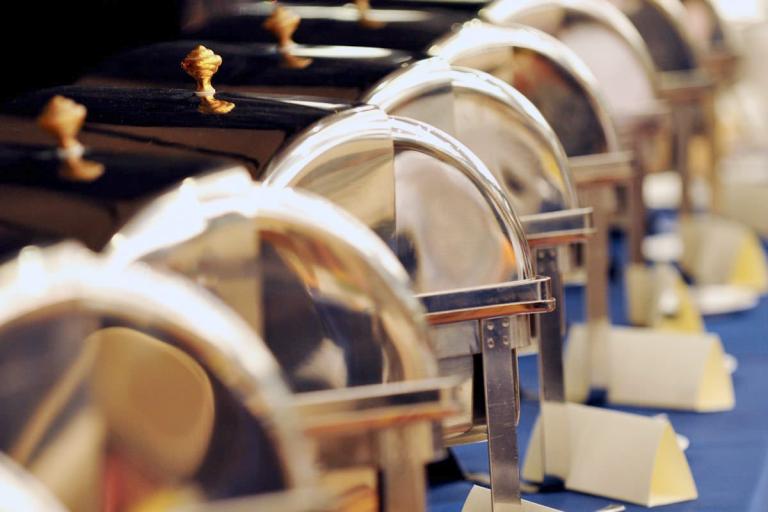 A long line of shining chafing dishes with placquards 