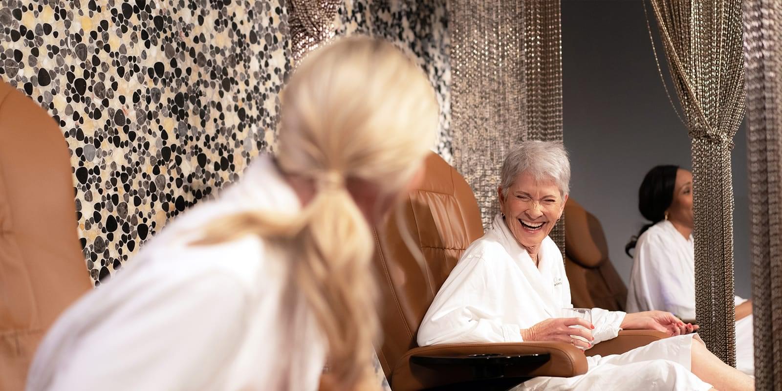 Image of three women sitting in spa chairs with spa robes on