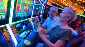 A man watches in awe as the woman next to him win big on a slot machine