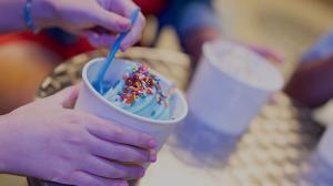 A child holding a cup of frozen yogurt with sprinkles